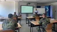 Soldaten sitzen in einem Unterrichtsraum. Ein Dozent steht an der Smartboard.
