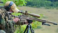 Ein deutscher Soldat visiert mit seinem Gewehr ein Ziel unterhalb seiner Stellung an.