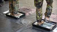 Soldaten stehen mit Stiefeln in einer Wanne