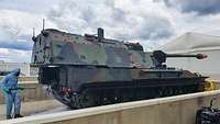 Eine Panzerhaubitze 2000 wird von einem Soldaten in Schutzkleidung eingesprüht