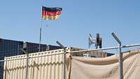 Ein Lautsprechermast steht hinter einem Zaun, links daneben weht die deutsche Flagge