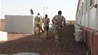 Mehrere Soldatinnen und Soldaten rennen auf einen Bunker zu