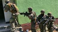 Vier Soldaten stehen außerhalb eines Gebäudes mit ihren Gewehren vor einer halb geöffneten Tür