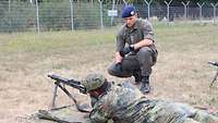 Ein österreichischer Soldat kniet neben einem deutschen Kameraden, der sich ein Gewehr einrichtet.