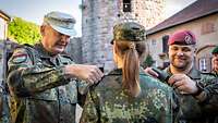 Zwei Soldaten stehen einer Soldatin gegenüber und wechseln ihre Dienstgradschlaufen.