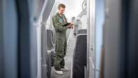 Kontrolle der Ausstattung Ein Techniker der Bundeswehr steht im Gang eines Airbus A321LR und macht Notizen auf einem Klemmbrett