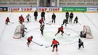 Training mit zwei Gruppen Zwischen eng stehenden Toren spielen Eishockeyspielerinnen vier-gegen-vier beobachtet von Trainern