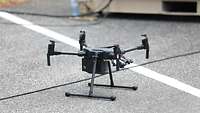 A black drone with four propellers on the ground