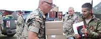Stabsfeldwebel Ingo P. bei der Vergabe der Verpflegung Ein Soldat trägt mehrere Verpflegungsboxen. Im Hintergrund sind weitere Soldaten zu sehen.