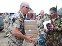 Stabsfeldwebel Ingo P. bei der Vergabe der Verpflegung Ein Soldat trägt mehrere Verpflegungsboxen. Im Hintergrund sind weitere Soldaten zu sehen.