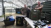 SIBCRA-Team Zwei Soldaten stehen unter einem Tarnnetz an einem Tisch mit Rucksäcken,Transportkoffer und Geräten
