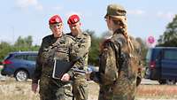 Eine Soldatin spricht mit einer weiteren Soldatin und einem Soldaten.