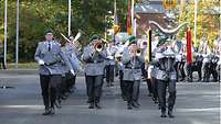 Militärmusiker marschieren musizierend eine Straße entlang