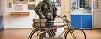 ein Wehrmachtssoldat mit seinem Fahrrad in einer Ausstellungshalle