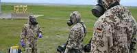 ABC-Übung in Kanada Soldaten in Schutzanzügen und mit ABC-Masken stehen im Gelände mit ihrer Ausrüstung