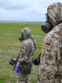 ABC-Übung in Kanada Soldaten in Schutzanzügen und mit ABC-Masken stehen im Gelände mit ihrer Ausrüstung