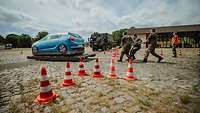 Drei Soldaten scheiben ein Auto vor einen Lkw auf eine Teststrecke