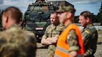 Mehrere Soldaten unscharf im Vordergrund stehen vor einem Lkw