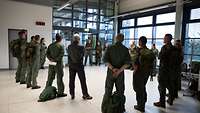 Soldatinnen und Soldaten stehen in einem Kreis zusammen und besprechen sich