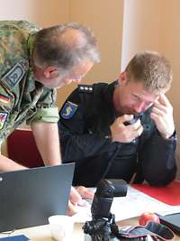 Ein Soldat spricht mit einem Polizisten über mögliche Amtshilfe.