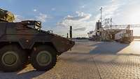 Ein GTK Boxer steht im Hafen bereit, während ein Lkw in den Bauch einer Fähre rollt