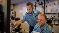 Zwei Marinesoldaten in blauer Arbeitsuniform im Gespräch.