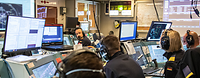 Team OPZ Mehrere Marinesoldaten in blauer Arbeitsuniform sitzen vor Computerkonsolen, Monitoren und Laptops.