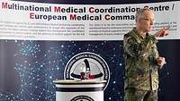 A soldier gestures in front of a podium.