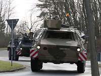Zwei Radpanzer fahren hintereinander auf einer Straße.