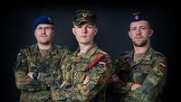 Portrait von drei Soldaten vor schwarzem Hintergrund, die mit verschränkten Armen in die Kamera blicken