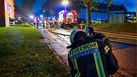Mehrere Einsatzfahrzeuge der Feuerwehr und Feuerwehrleute vor einem Gebäude