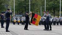 Vizeadmiral Dr. Thomas Daum entpackt eine große Fahne in schwarz-rot-gold für das ZDigBw.