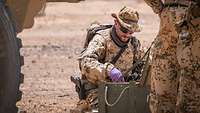 Ein Soldat sitzt hinter einer Munitionskiste und verteilt Munition