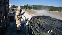 Ein Soldat im Schutzanzug sprüht einen Panzer ab