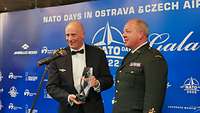 Zwei Generale in Uniform vor einem Mikrofon mit einem Preis 