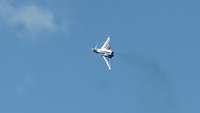 Ein bunter Eurofighter fliegt bei blauem, fast wolkenlosen Himmel.