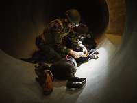 Ein Soldat übt mit einem Polizist an einem Dummy Ein Soldat und ein Polizist knien in einem dunklen Tunnel vor einem schwer verletzten Hunde-Dummy und legen eine Infusion