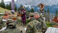 Ein Militärpfarrer hält einen Gottesdienst vor einer Bergkulisse.