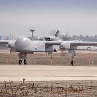 Eine Aufklärungsdrohne Heron TP mit rotierenden Propellern auf dem Rollfeld