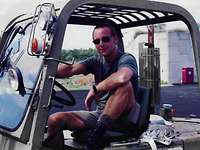 Der Lufttransportfeldwebel Michael Mieruch Ein Soldat, mit Sonnenbrille, in grüner kurzer Hose und grünem T-Shirt, sitzt in einem Gabelstapler