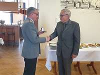 Dr. Schoeps und Dr. Mees Ein Soldat überreicht eine Medaille an einen Zivilisten