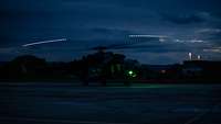 Ein Hubschrauber mit drehendem Rotor bei Nacht.