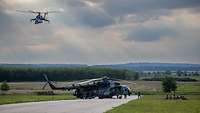 Ein Kampfhubschrauber sichert aus der Luft den Start eines Transporthubschraubers.
