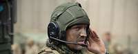 Ein Soldat mit grüner Tarnfarbe im Gesicht und einem Panzerhelm mit Sprechsatz
