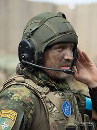 Ein Soldat mit grüner Tarnfarbe im Gesicht und einem Panzerhelm mit Sprechsatz