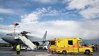 An aircraft of the German Air Force and ambulances on the taxiway of an airport