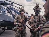 Zwei bewaffnete KSK-Soldaten stehen vor einem Hubschauber.