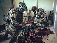 Zwei KSK-Soldaten versorgen in einem Gebäude einen am Boden liegenden Soldaten mit einer schweren Beinverletzung.