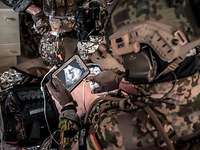 Ein KSK-Soldat bedient ein mobiles Gerät während der Versorgung eines verwundeten Soldaten.
