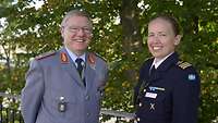 A male and a female soldier stand next to each other and smile at the camera